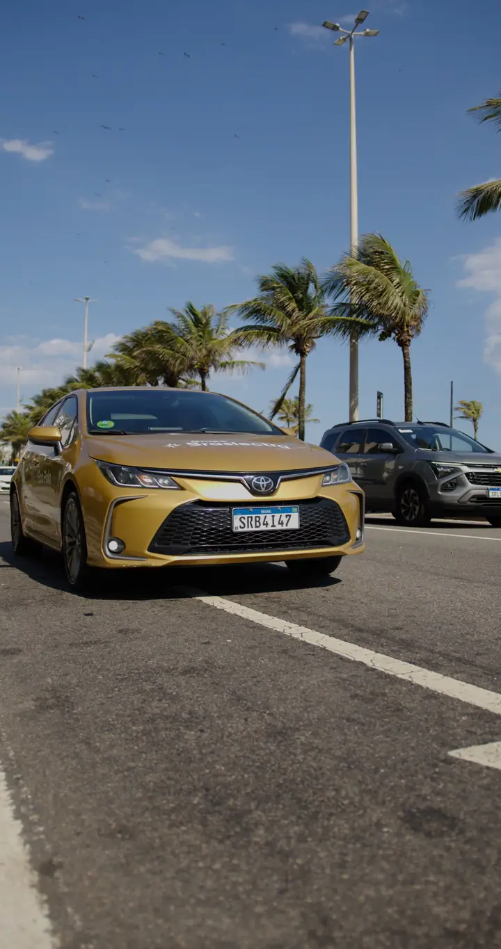 Toyota Corolla dourado da frota Braslectra em avenida com palmeiras